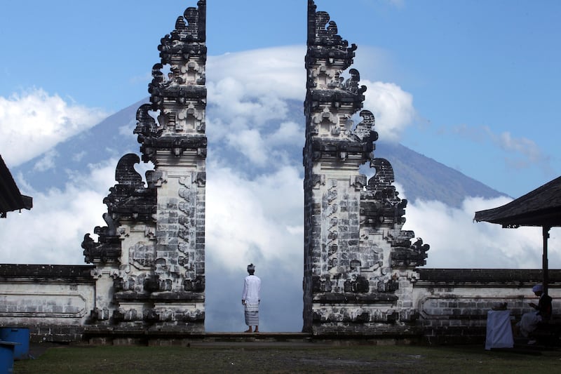 A man watches Mount Agung volcano almost covered with clouds as he stands at a temple in Karangasem, Bali, Indonesia. Firdia Lisnawati / AP Photo