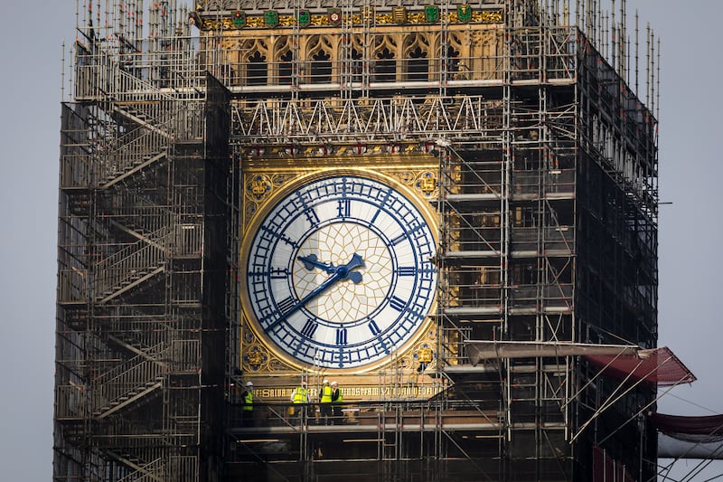 Workers stand on scaffolding underneath the clock face known as Big Ben with the clock hands seen restored to the original Prussian blue colouring in London,  September 2021. EPA