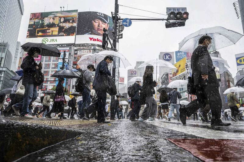 People use their umbrellas to shelter from the rain as they walk through Shibuya district. AFP