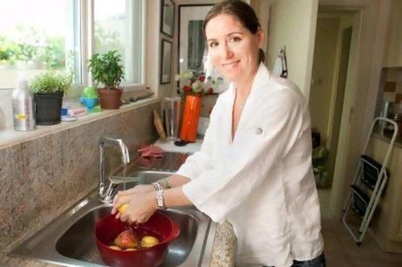 Julie Woods washes the vegetables over a dish to hold water that will be used later to water plants at her Dubai villa.