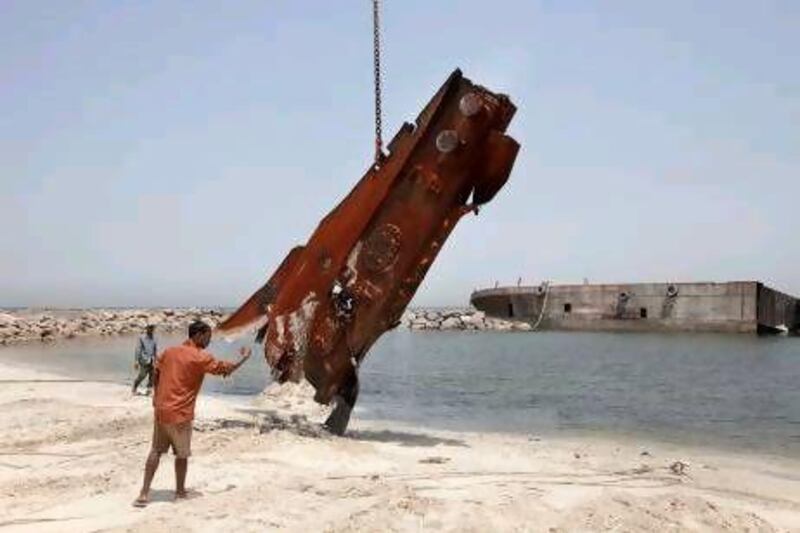 :Workers on Monday dismantle the barges that were brought on the shores of Sharjah waters by the bad weather.