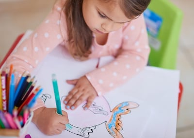 High angle shot of a little girl colouring in a picture at home. Getty Images