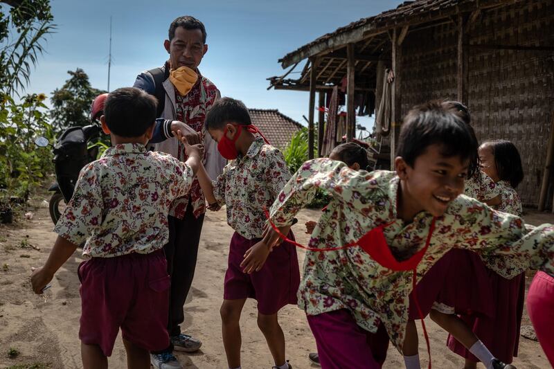 Pupils shake hands with their teacher Parmin as he makes a home visit to students who have poor cellular service and cannot learn online at the remote area in Senden village at slope of mount Merapi and Merbabu in Selo, Boyolali, Central Java, Indonesia. Getty Images