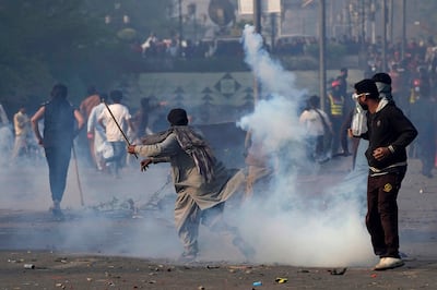 A supporter of former Prime Minister Imran Khan hurls back a tear gas shell fired by riot police during clashes in Lahore on Wednesday, March 15, 2023. AP