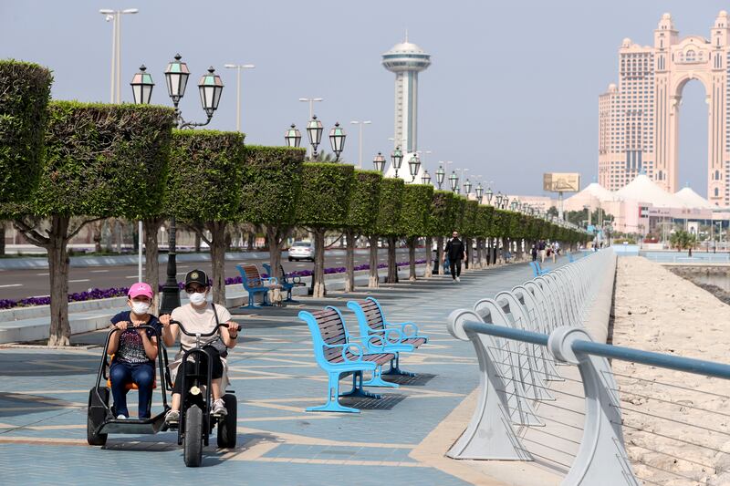 Residents ride e-scooters along the Corniche in Abu Dhabi. Khushnum Bhandari / The National 

