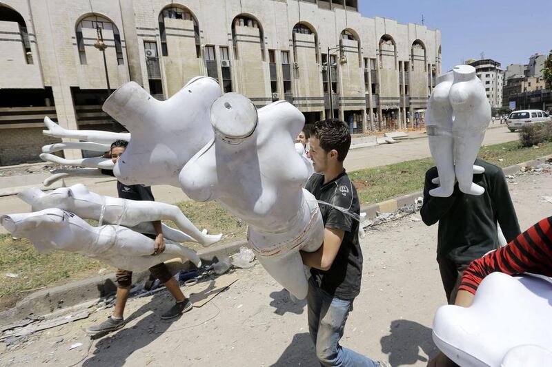Young Syrian men carry mannequins in a destroyed neighbourhood in the Old City of Homs, Syria.  Joseph Eid / AFP