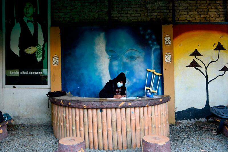 A student wearing a facemask sits the grade 12th board exam at an outdoor area in the school amid the Covid-19 coronavirus pandemic in Kathmandu.  AFP