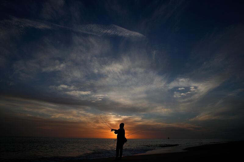 A man casts a fishing pole into the ocean during sunset in Newport Beach, California. AP Photo