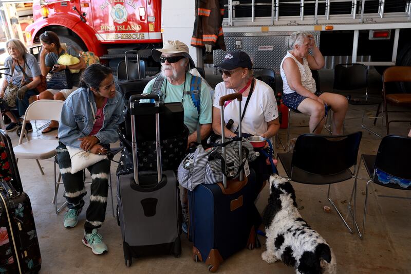 Lisa, Ray and Lucia West and their dog wait to be taken off the island. Getty / AFP