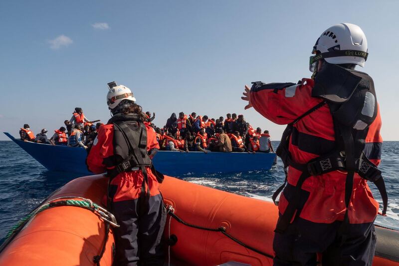 Members of the German charity Sea-Watch 3 rescue ship team help migrants on a deflating dinghy during a rescue operation in the Mediterranean Sea, February 26, 2021. Picture taken February 26, 2021. Selene Magnolia/Sea-Watch/Handout via REUTERS ATTENTION EDITORS - THIS IMAGE HAS BEEN SUPPLIED BY A THIRD PARTY. MANDATORY CREDIT