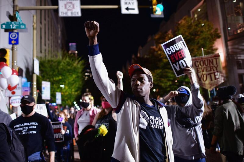 Tyrik Wilson, 34, raises his arm in solidarity with other activists while demonstrating across the street from where votes are being counted in Philadelphia, Pennsylvania. Reuters