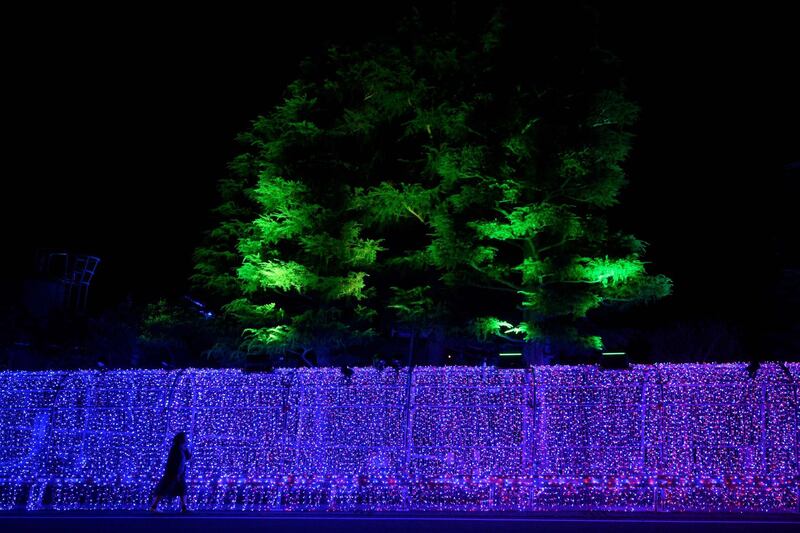 A woman walks along a wall decorated with ornate lighting in front of a hotel where the New Zealand rugby team is putting up in Beppu at the sport's world cup. AFP