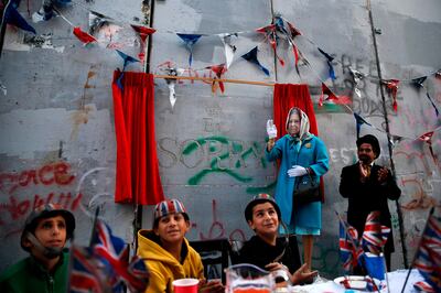 An actor dressed up as Queen Elizabeth and Palestinian children from the al-Aida refugee camp attend an event held by secretive British street artist Banksy to apologise for the 100th anniversary of the Balfour Declaration on November 1, 2017 at his Walled-Off Hotel in Bethlehem in the occupied West Bank.
The queen revealed a plaque carved in stone saying "Er, Sorry," playing on the common initials for Elizabeth Royal. / AFP PHOTO / AHMAD GHARABLI