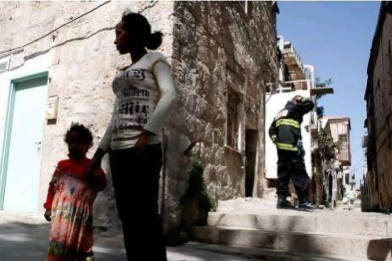 An Eritrean woman with her daughter outside an apartment in Jerusalem that was set ablaze. Israel said it will step up deportation plans for 25,000 African migrants and jail those who try to enter the country.