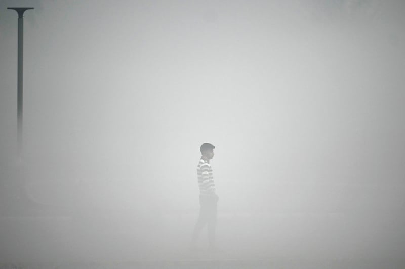 A pedestrian walks along the roadside amid heavy smoggy conditions in New Delhi. AFP