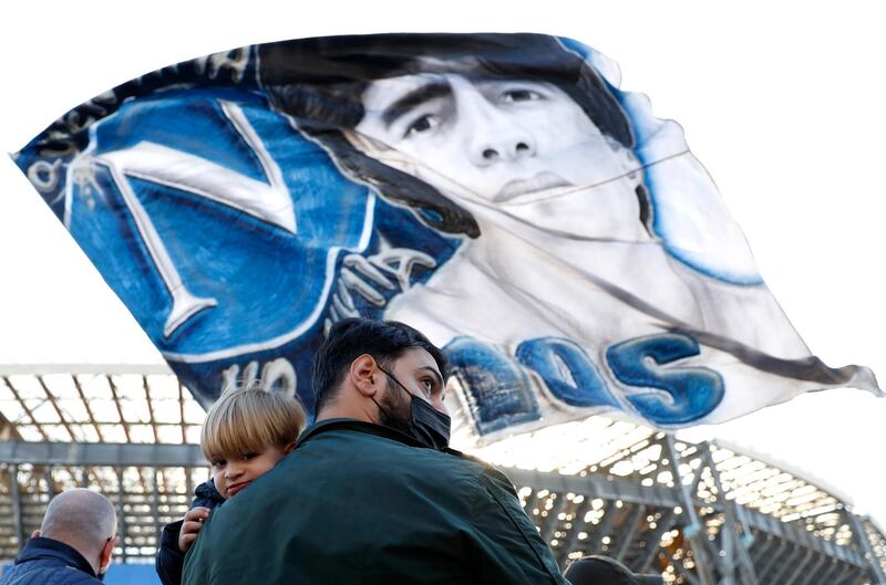A man and child outside the Stadio San Paolo in Naples as a Diego Maradona flag is waved in tribute to the Argentine football legend following his death. Reuters