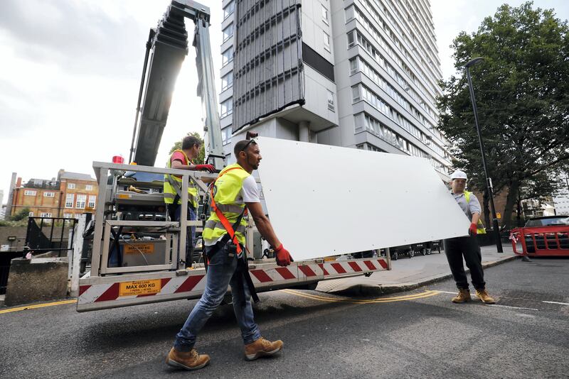 Workers remove panels of external cladding from the facade of Braithwaite House in London, on July 3, 2017, in the wake of the Grenfell Tower fire.
Communities Secretary Sajid Javid announced in the Commons, that all 181 tested samples of cladding had failed safety tests. / AFP PHOTO / Tolga AKMEN
