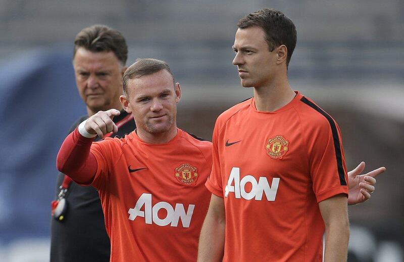 Manchester United's Wayne Rooney, left, talks with Jonny Evans as manager Louis van Gaal, left, watches during training for the their 2014 Guinness International Champions Cup soccer match against Real Madrid at Michigan Stadium in Ann Arbor, Michigan on Friday, Aug. 1, 2014. (AP Photo/Paul Sancya)