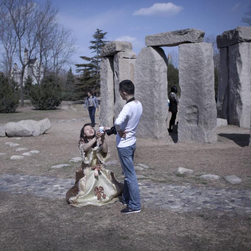Tourists pose for a photo by a mini replica of the Stonehenge.