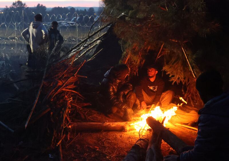 Migrants gather near a fire on the Belarusian-Polish border. Reuters