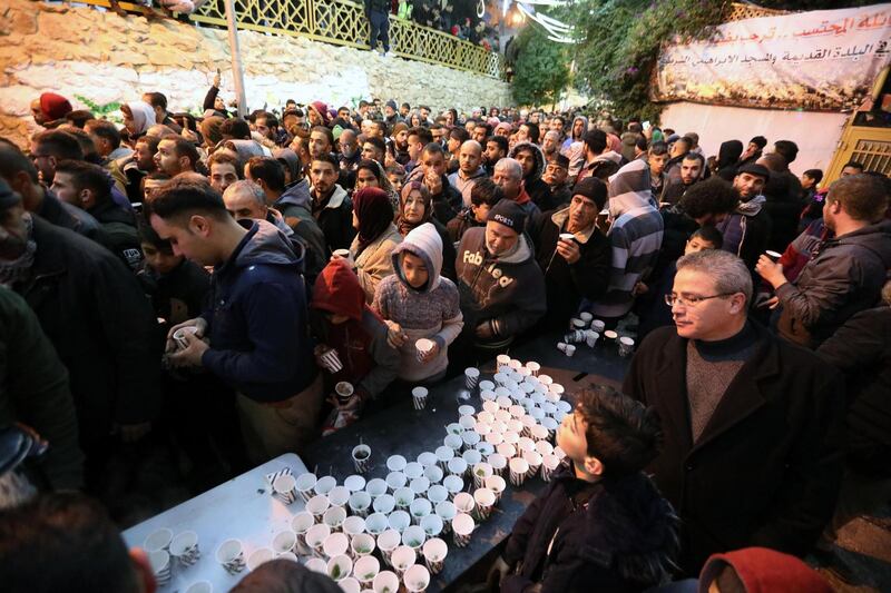 People are served free pastries, as Palestinian Muslim worshippers gather for an early morning prayer around the Ibrahimi Mosque or the Tomb of the Patriarch in Hebron, West Bank.  EPA