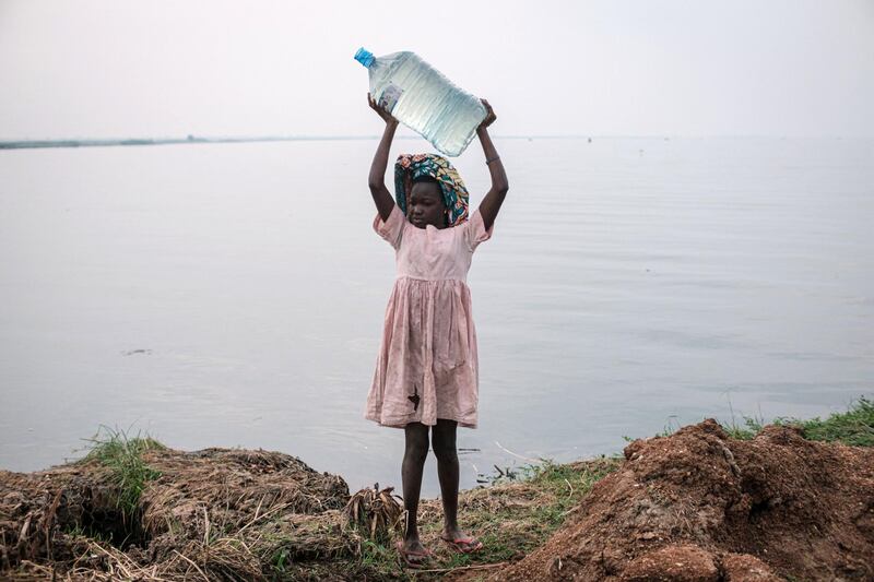A girl holds a bottle of water above her head after fetching water from the Nile river near the Kisomere village in western Uganda, on January 28, 2020. - When exploitable crude oil deposits were discovered in 2006 in the Lake Albert region, Uganda began to imagine itself as a new oil Eldorado. But 14 years later, the mirage has faded, and it is still waiting to extract its first drops of black gold.
This discovery had raised wild hopes in a country where 21% of the population lives in extreme poverty. The Ugandan government saw the prospect of earning at least $1.5 billion a year and increasing its GDP per capita from $630 to over $1,000. (Photo by Yasuyoshi CHIBA / AFP)