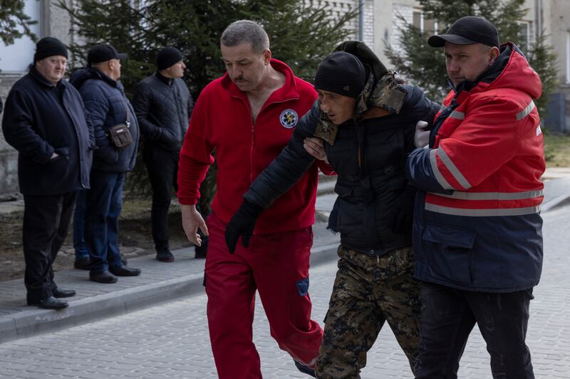 A man injured in air strikes on a training site in Yavoriv, western Ukraine, is helped by medical staff. Getty