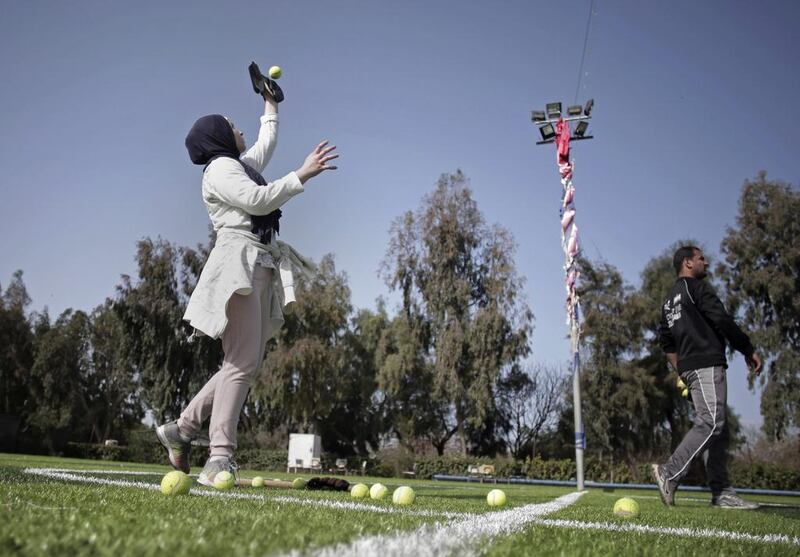 The female players wear hijabs, not helmets, toss around tennis balls, not baseballs and their leather gloves have been replaced by black imitations knitted from fabric.