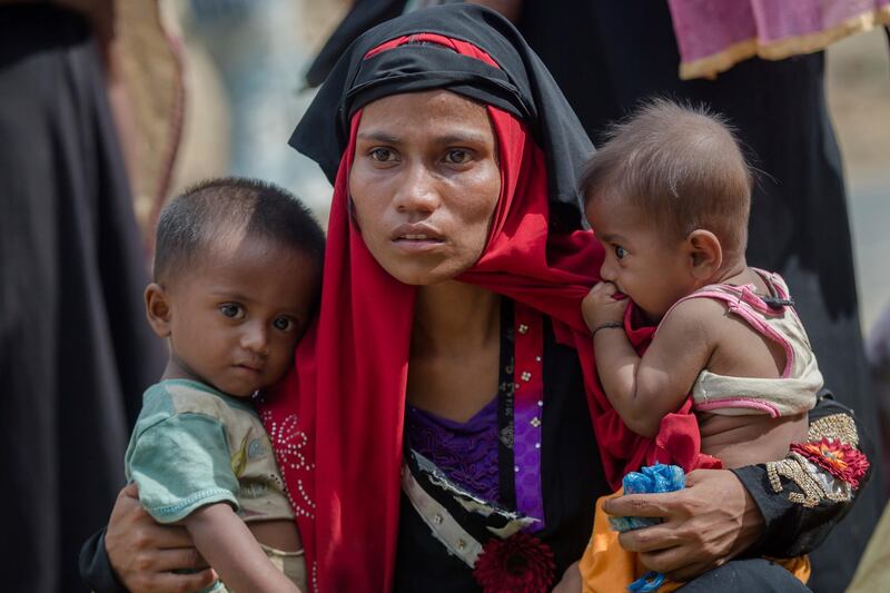 FILE - In this Oct. 22, 2017, file photo, Rohingya Muslim woman, Rukaya Begum, who crossed over from Myanmar into Bangladesh, holds her son Mahbubur Rehman, left, and her daughter Rehana Bibi, after the government moved them to newly allocated refugee camp areas, near Kutupalong, Bangladesh. Myanmar, a predominantly Buddhist nation of 60 million, was basking in international praise just a few years ago as it transitioned to democracy after a half-century of dictatorship. Since then, a campaign of killings, rape and arson attacks by security forces and Buddhist-aligned mobs have sent more than 850,000 of the country's 1.3 million Rohingya fleeing. (AP Photo/Dar Yasin, File)