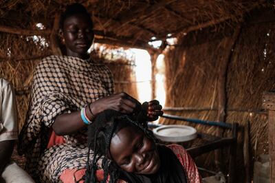 A Sudanese woman braids her sister's hair in their hut in the Rabang camp for internally displaced persons in Rabang, in the Nuba Mountains, Sudan. AFP