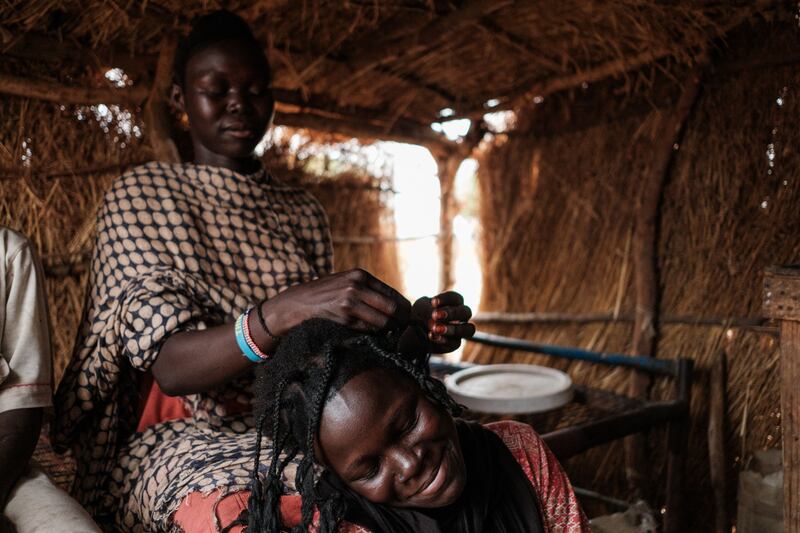 A woman braids her sister's hair in the Rabang displacement camp.
