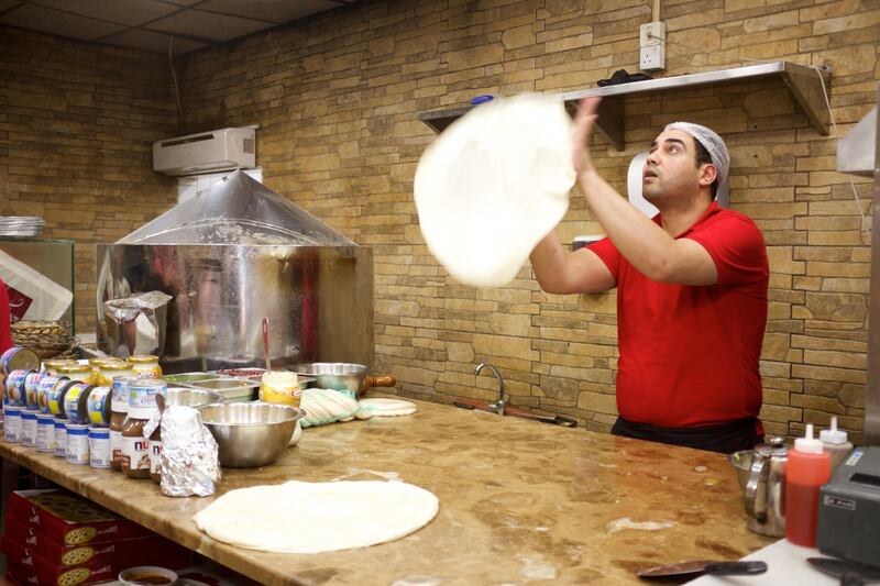 A chef at a restaurant in old Dubai throws and spins dough to make the perfect Egyptian pizza. Courtesy: Frying Pan Adventures
