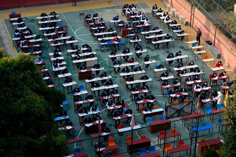 Pupils wearing facemasks sit the Grade 12  board exam at the school playground in Kathmandu.  AFP