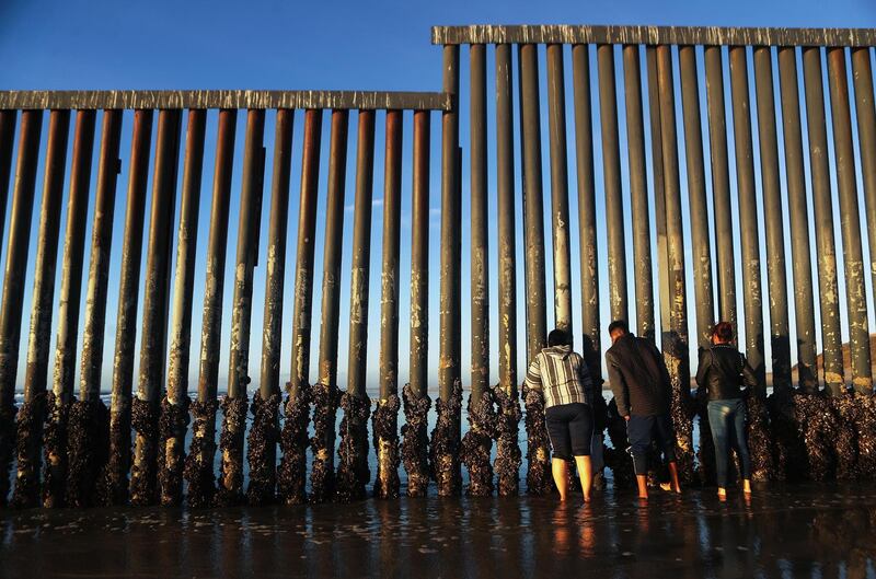People peer through the US-Mexico border fence, towards San Diego, at the Pacific Ocean, in Tijuana, Mexico. Getty