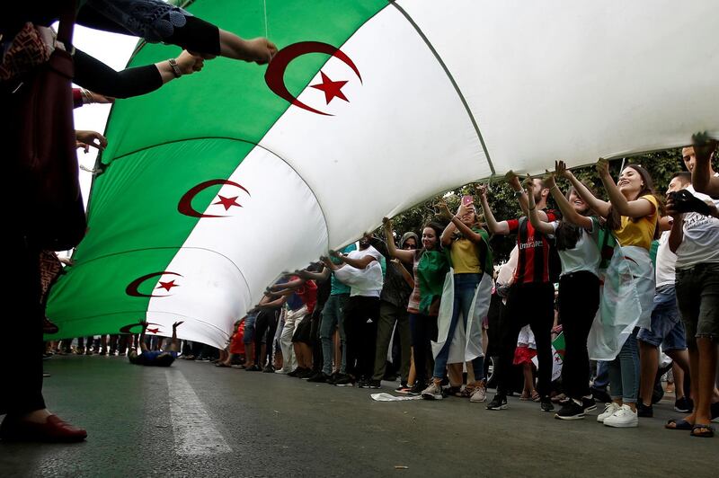 Demonstrators hold a national flag during a protest demanding the removal of the ruling elite in Algiers, Algeria. Reuters