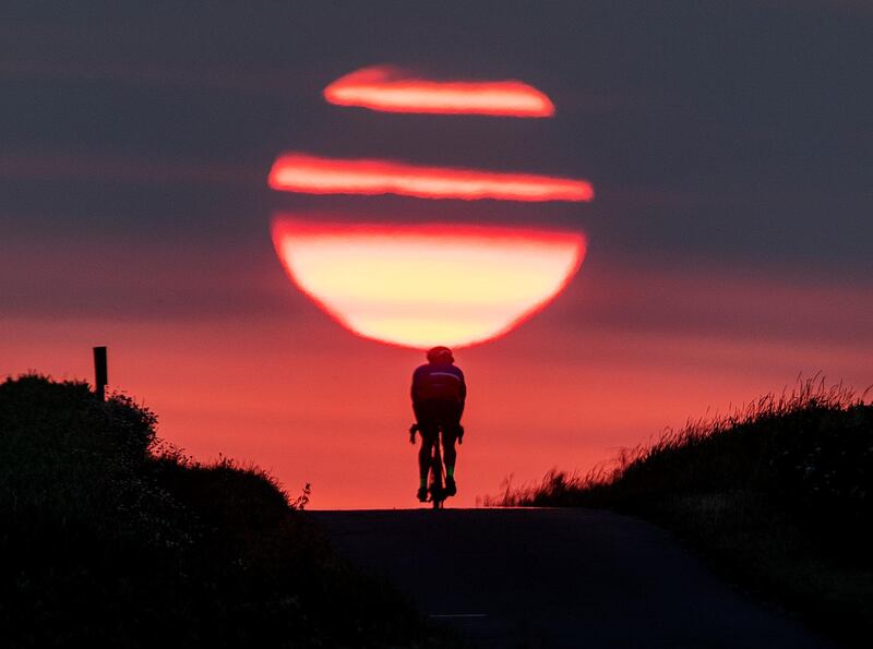 A man rides his bike on a small path as the sun rises in Frankfurt, Germany.  AP