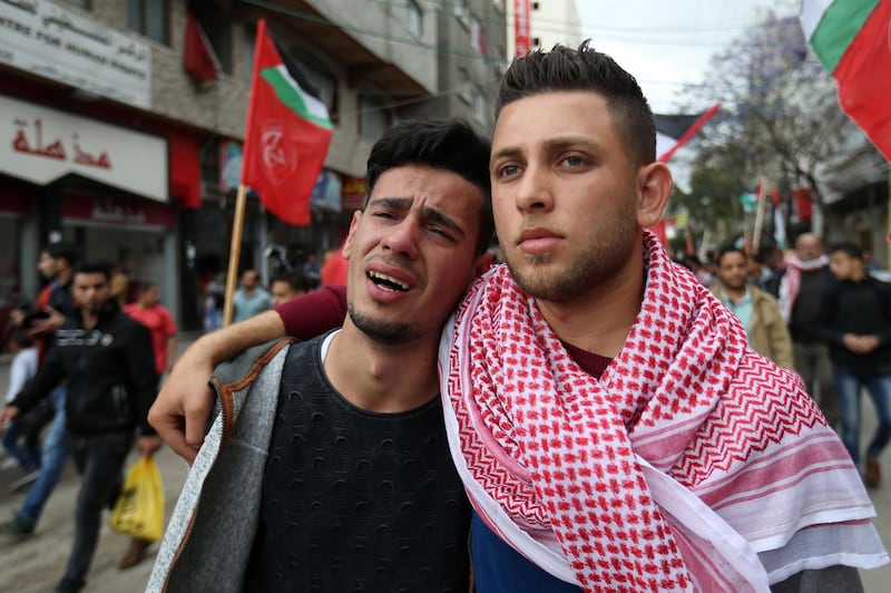 TOPSHOT - Palestinian youths mourn during the funeral of journalist Ahmed Abu Hussein in Jabalia in the northern Gaza Strip on April 26, 2018, after he succumbed to his injuries from two weeks before when he was shot by Israeli forces while covering demonstrations on the Gaza border. / AFP PHOTO / MOHAMMED ABED