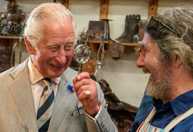 Britain's Prince Charles holds a magnifying glass as he jokes with Michael Johnson at a copper workshop, during his visit to Newlyn near Penzance in south-west England.  AFP