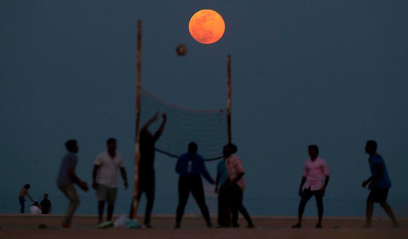 People play volleyball on the beach as the Pink Moon rises in the sky over the Salmiya district in Kuwait. AFP