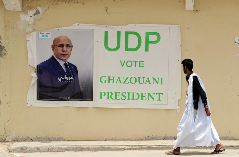 epaselect epa07660689 A man walks past an election poster of Mohamed Ould Cheikh Mohamed Ahmed Ghazouani, the ruling party's candidate, in a street of Nouakchott, Mauritania, 20 June  2019. Mauritania will vote on 22 June for the first round of a presidential election for a successor to President Mohamed Ould Abdel Aziz, who is stepping down after his second and final term in office.  EPA/MOHAMED MESSARA