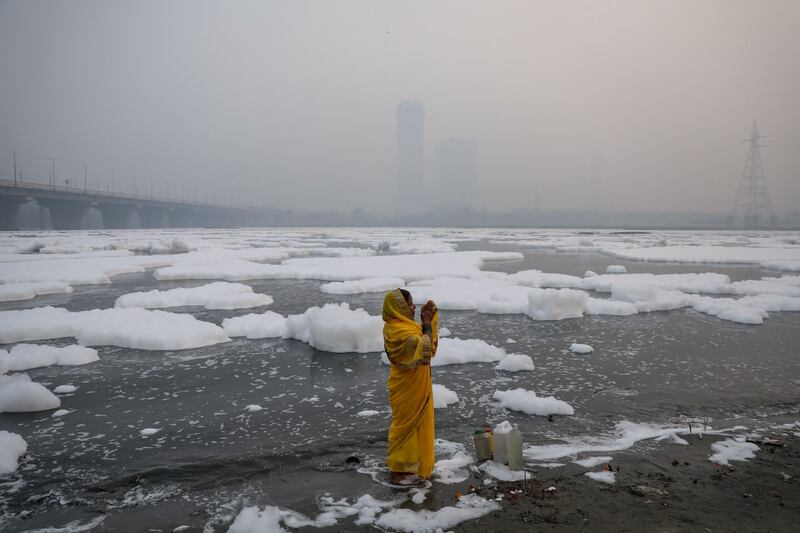 A woman prays on the banks of the polluted river Yamuna on a smoggy morning in New Delhi, on November 8, 2021. By Anushree Fadnavis, Pulitzer Prize finalist for Feature Photography. Reuters