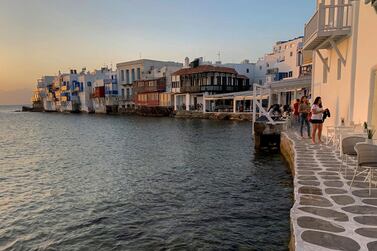 In this Tuesday, June 9, 2020 photo, visitors sit in bars in an area known as Little Venice on the Greek island of Mykonos. Business owners and locals officials on the Greek holiday island of Mykonos, a popular vacation spot for celebrities, club-goers, and high rollers, say they are keen to reopen for business despite the risks of COVID-19 posed by international travel. Greece will officially launch its tourism season Monday, June 15, 2020 after keeping the country's infection rate low. (AP Photo/Derek Gatopoulos)