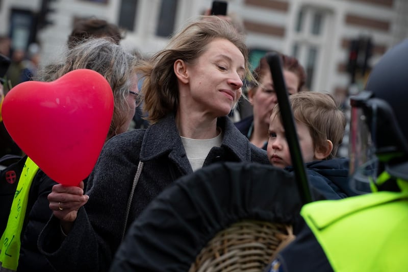A woman holding a child and a heart-shaped balloon challenges Dutch riot police after they broke up a demonstration against coronavirus-related government policies including the curfew and tight lockdown in Amsterdam, Netherlands, on March 21, 2021. AP