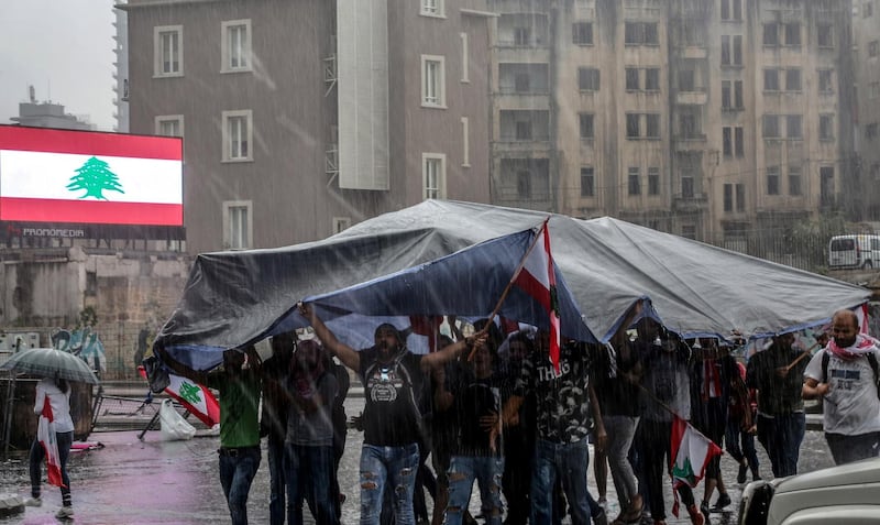 Protesters cover them selves by a tent as they block the Achrafieh highway in downtown Beirut. EPA