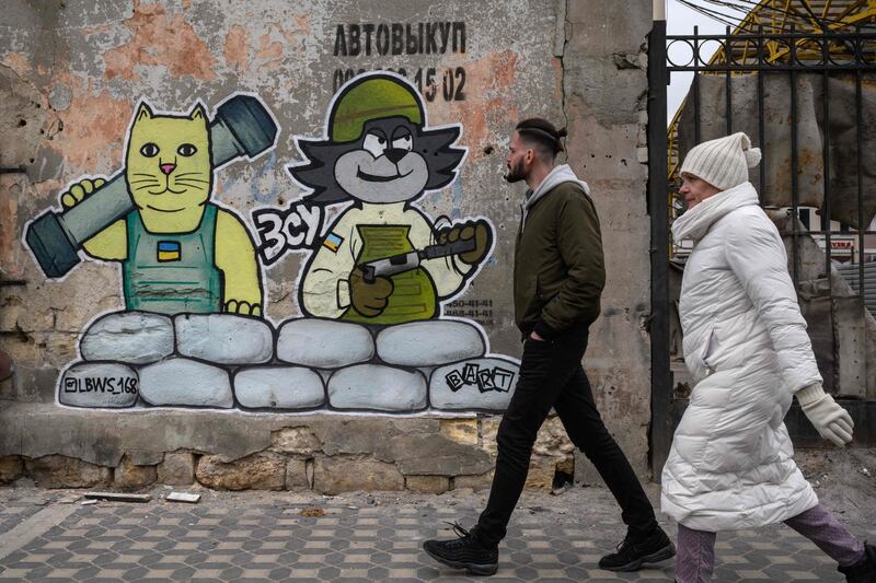 Pedestrians walk past artwork by the LBWS street art collective on a street in Odesa. AFP