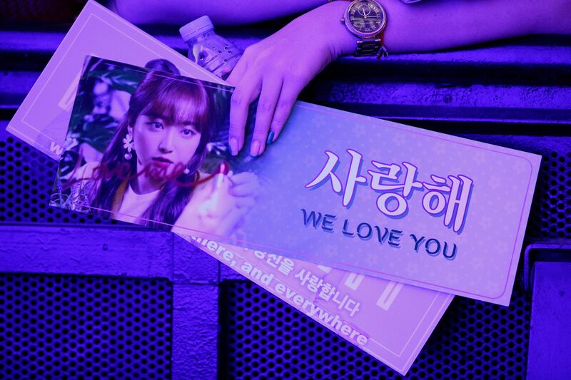 A fan holds printed material featuring K-pop stars at the concert.