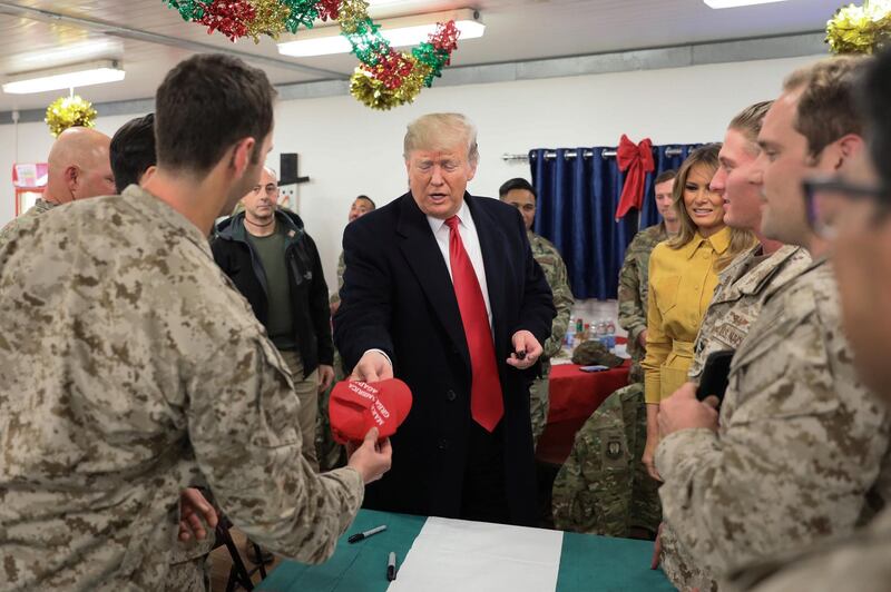 US President Donald Trump holds a Make America Great Again hat to sign as he and first lady Melania Trump greet military personnel at the dining facility during an unannounced visit to Al Asad Air Base, Iraq. Reuters