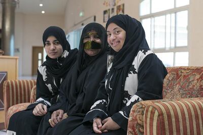 Zafarana Khamis sits with her daughters Hamda Al Hosani, left, and Mariam Al Hosani. The special-needs pupils have both won gold medals at the Special Olympics, in bowling and running respectively. Mona Al Marzooqi / The National