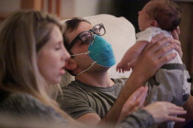 Emergency medicine physician Thomas Krajewski wears a mask as he holds his baby Cal with his wife Genevieve after finishing his shift in New Orleans, Louisiana. Reuters