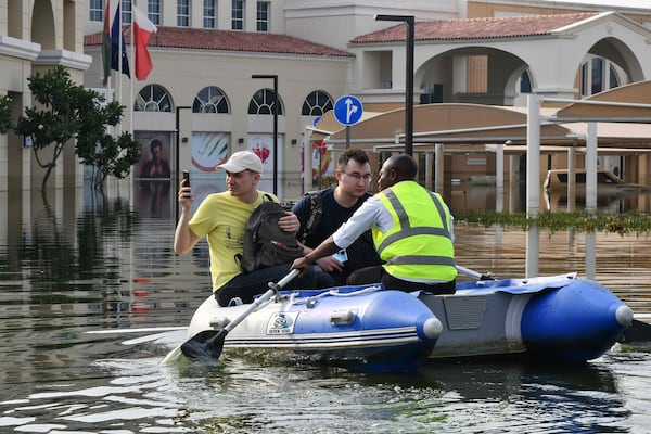 A staff member rows guests on an inflatable boat to the entrance of a hotel engulfed in floodwater in Dubai on April 22. AFP